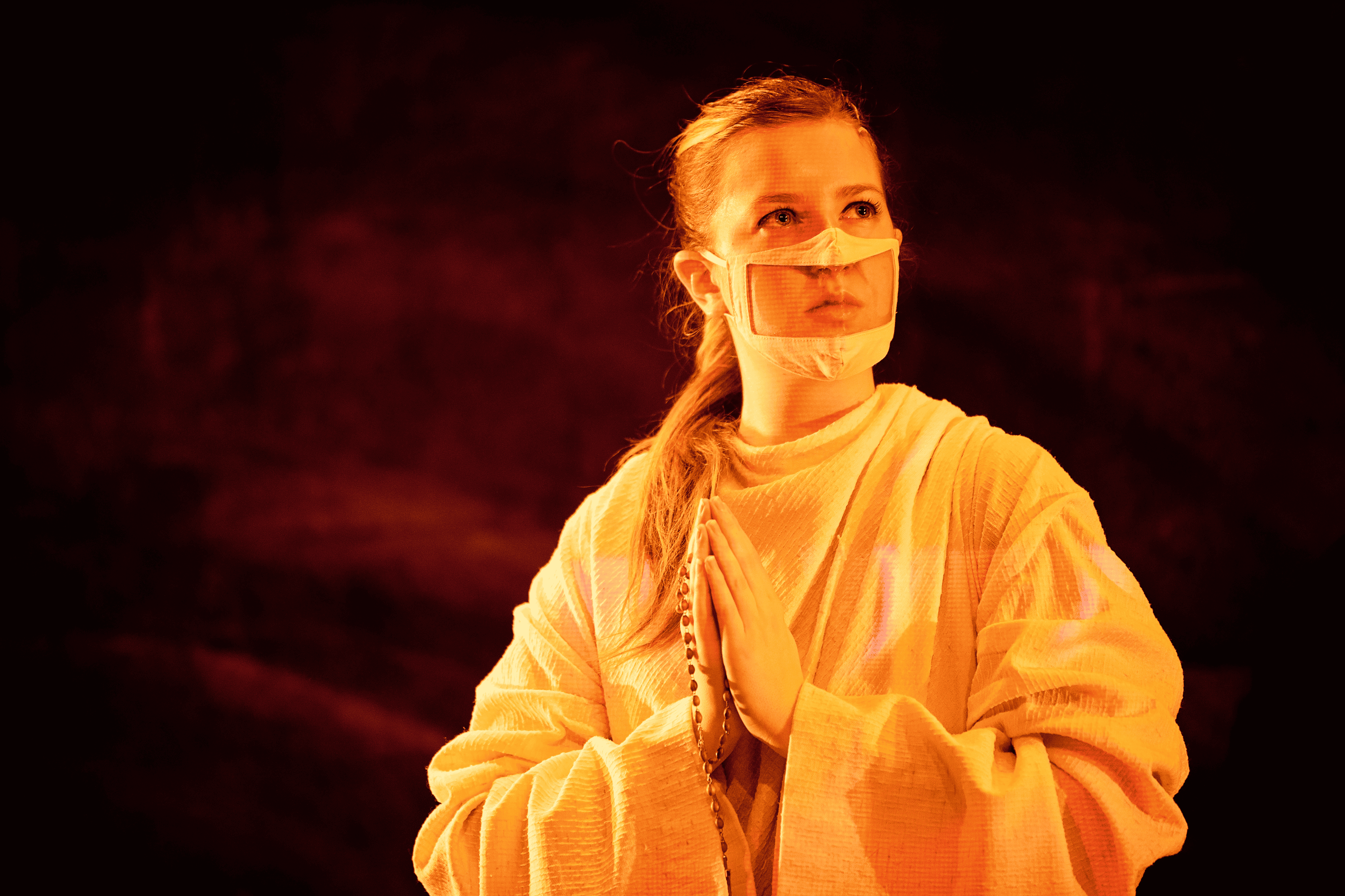 Woman wearing face mask with hands together like a prayer