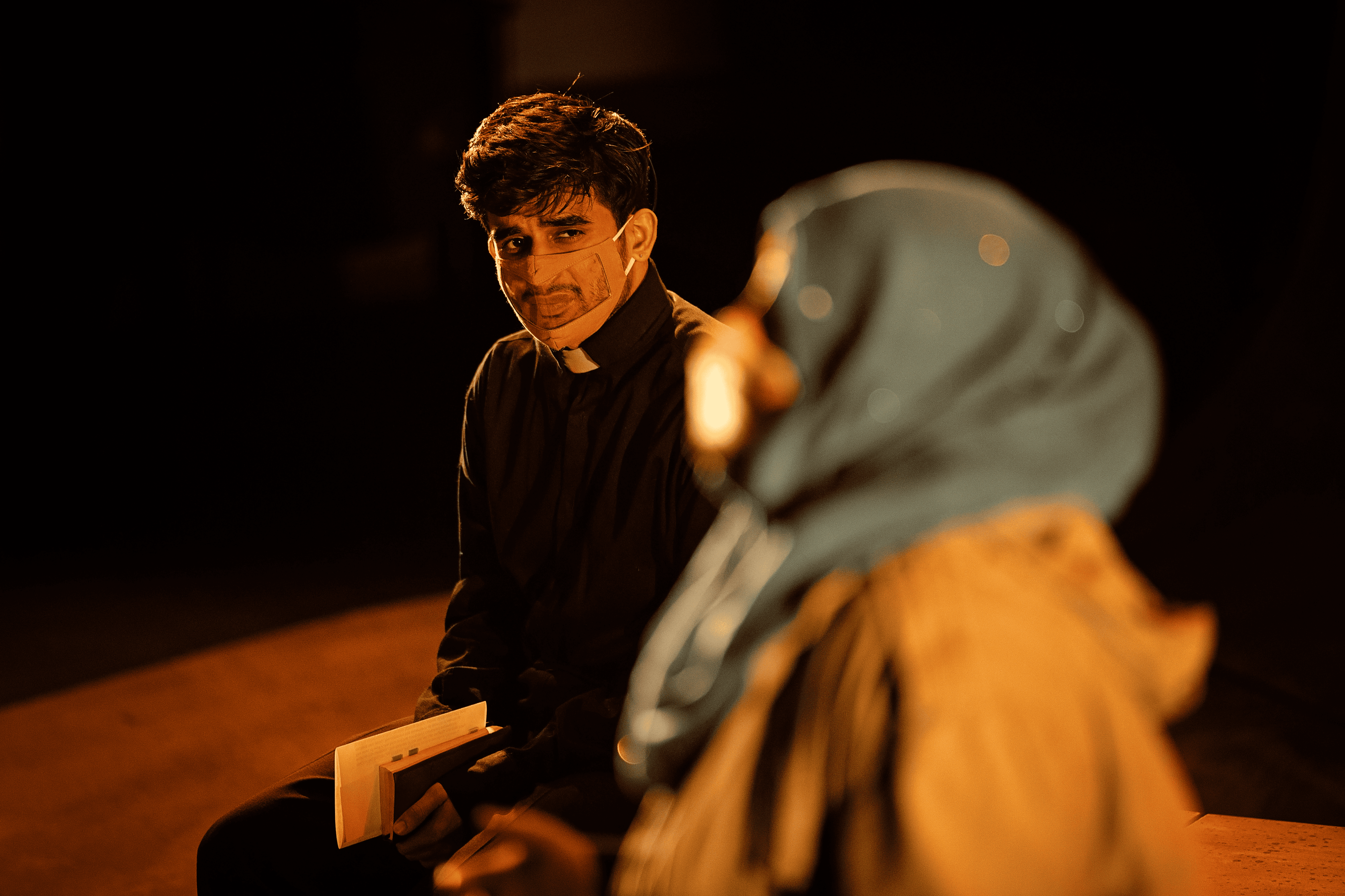 Priest looks to woman sitting next to him
