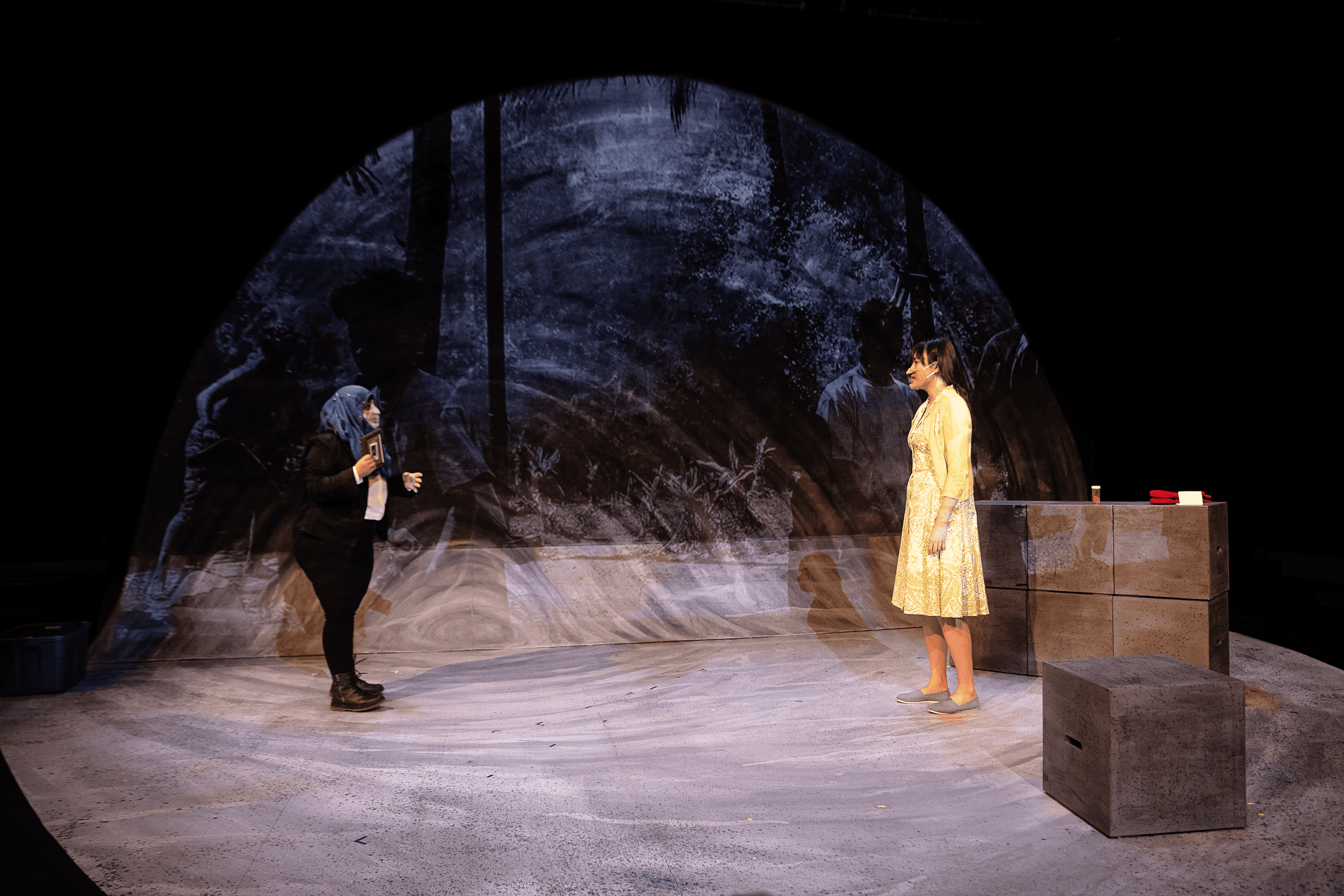 Two women facing each other with a video projection behind them