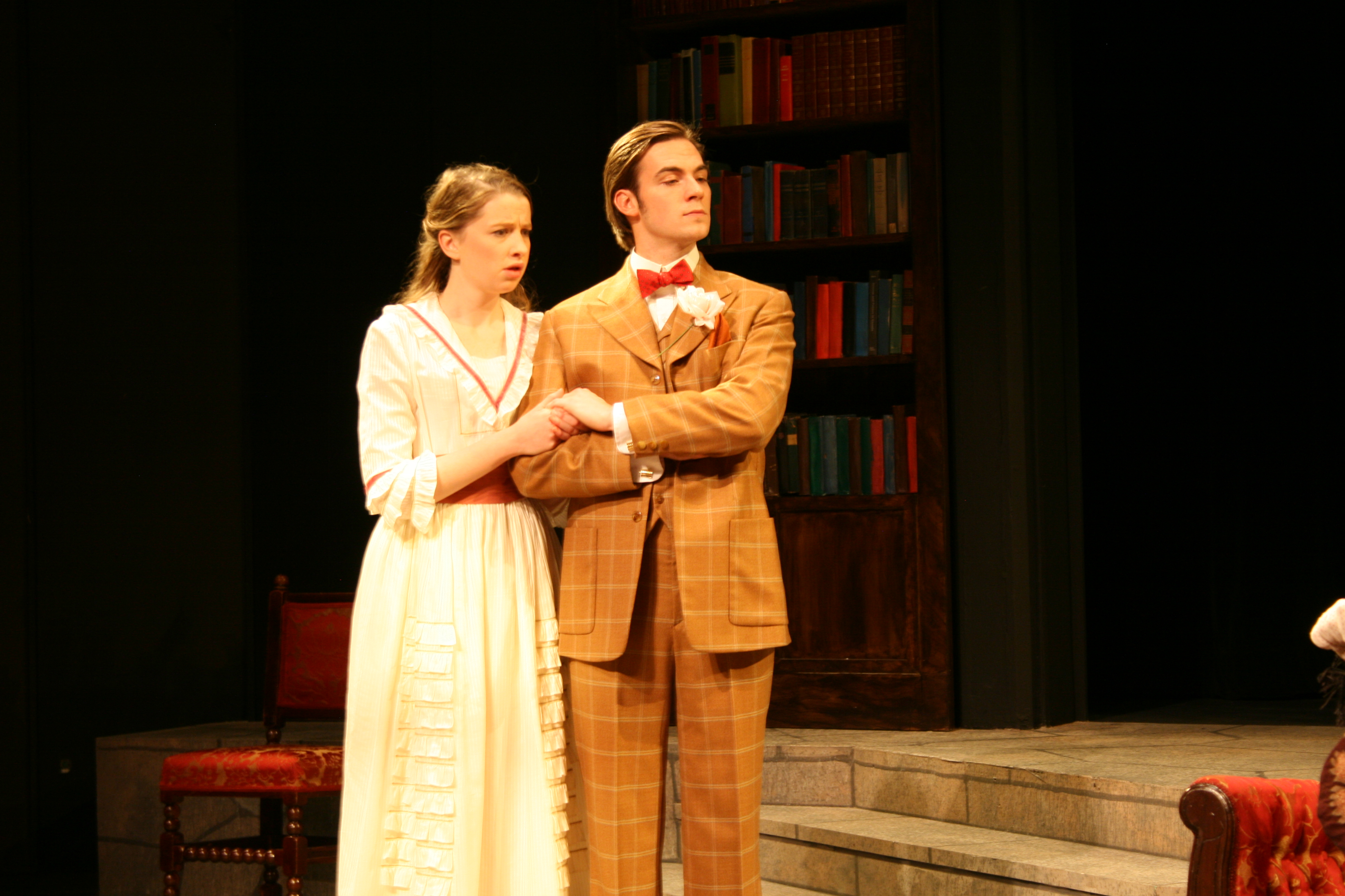 Woman in white and red dress linking arms with man in brown suit