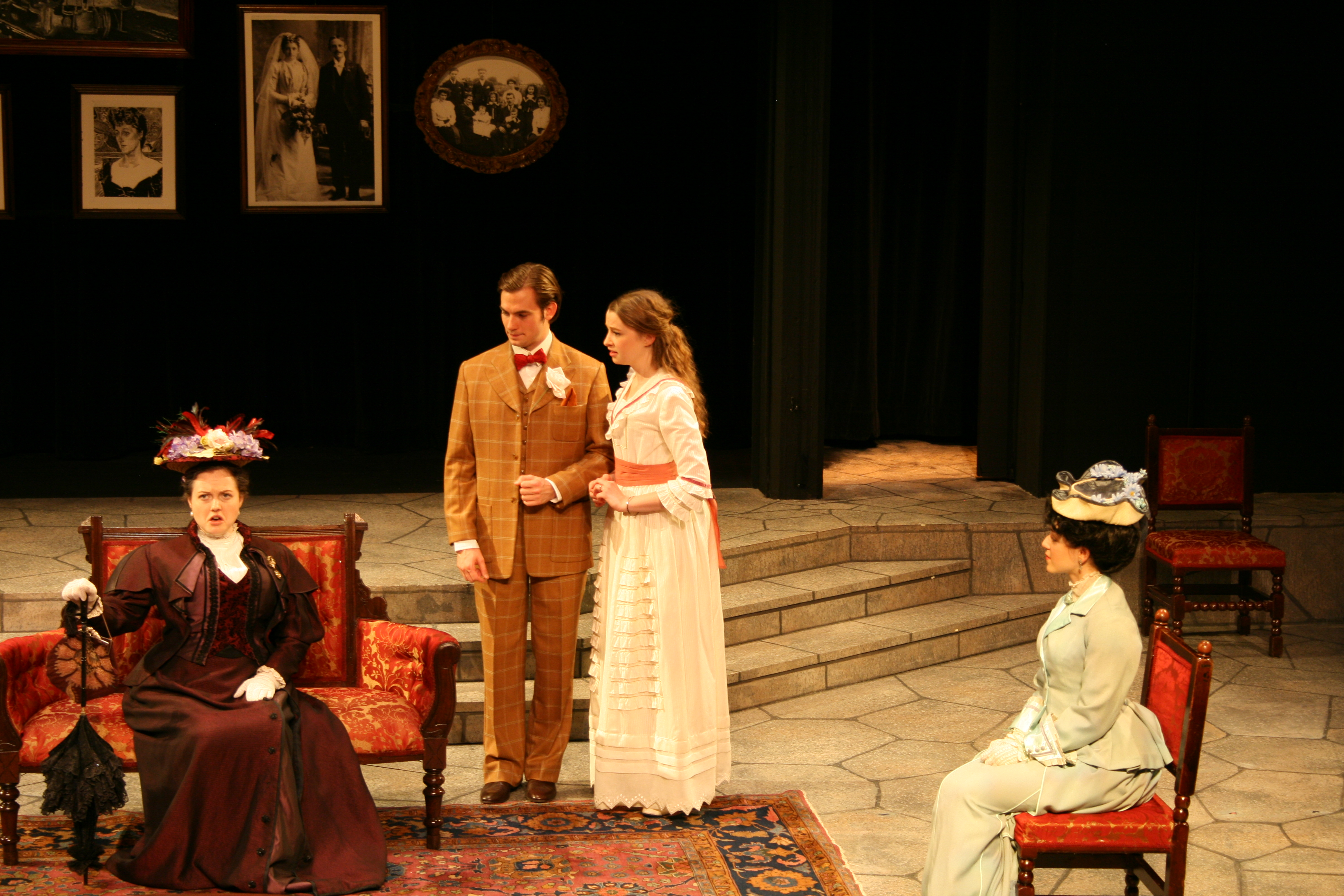 Two women and one man staring at strict-looking woman in red dress