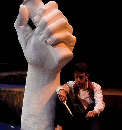 Man sitting holding knife in the play 'Julius Caesar'