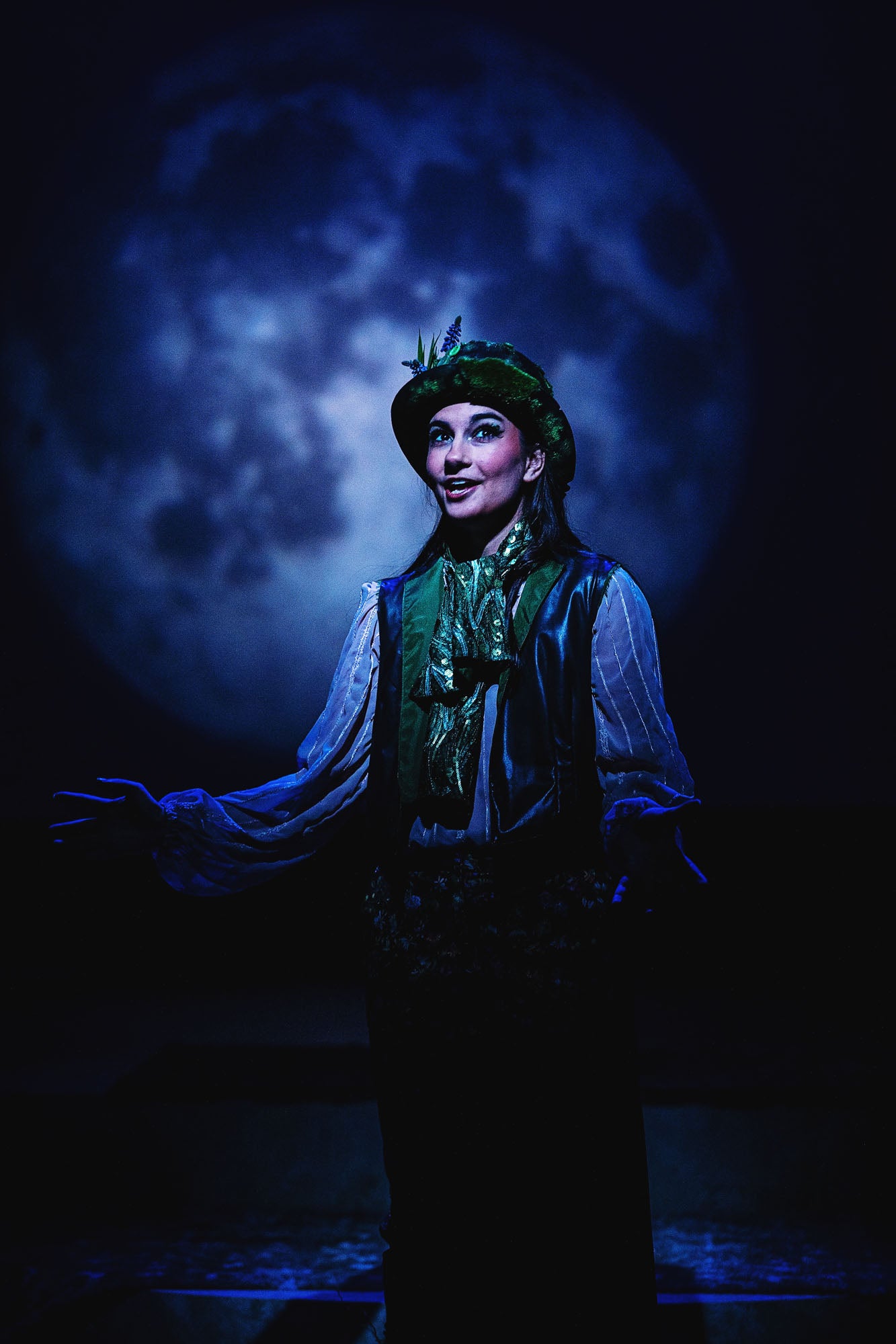 Puck (Daniela Milicevic) assures the audience that the play's events were but a dream, while a large moon looms in the background.