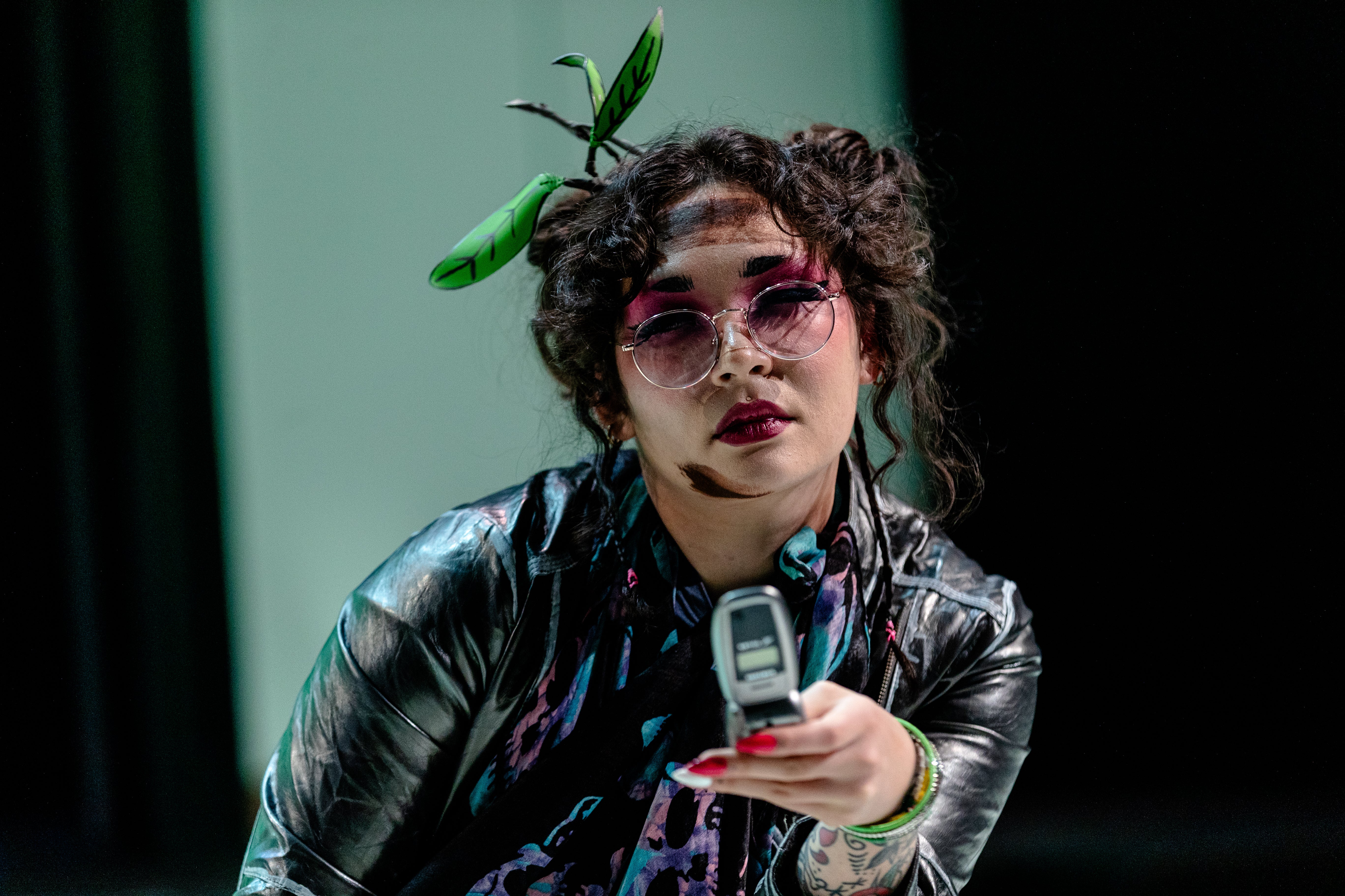 Tee holding her phone, glaring off-screen