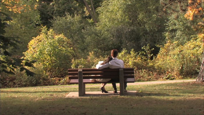 Eurydice and Orpheus sitting on a bench outside