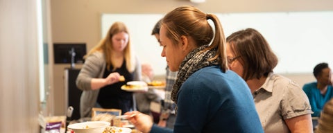 Graduate student putting food on plate during 2020 potluck 