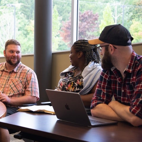 Three students talking in a conference room