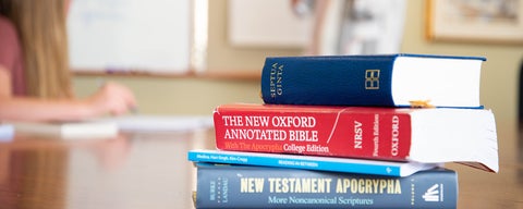 Theology textbooks stacked on classroom desk