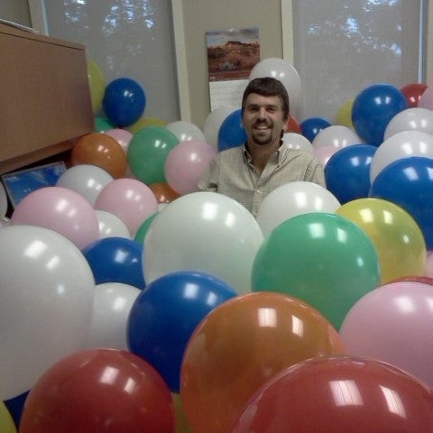 Jonathan Brubacher sitting in a pile of balloons