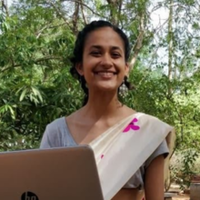 Image of Sriranjini Raman smiling at the camera and holding a laptop