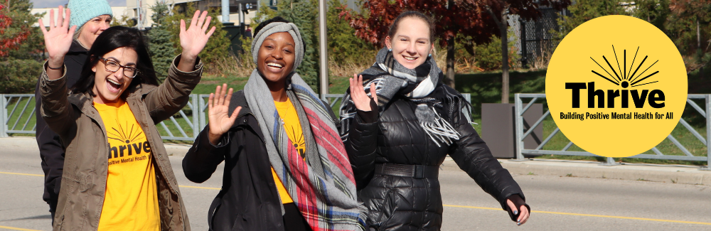 Three students participating in the Thrive walk waving and smiling at the camera