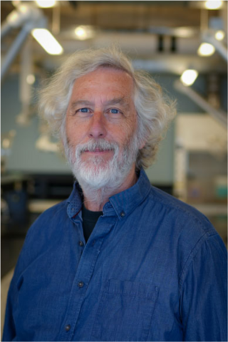 Dr. David Cory, wearing a blue collared shirt, stands in a lab.