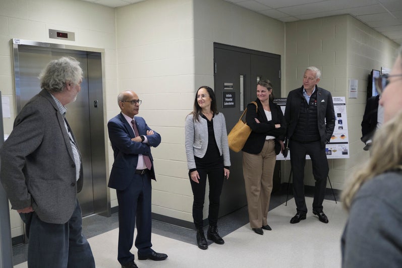 A group of people talking in front of an elevator.