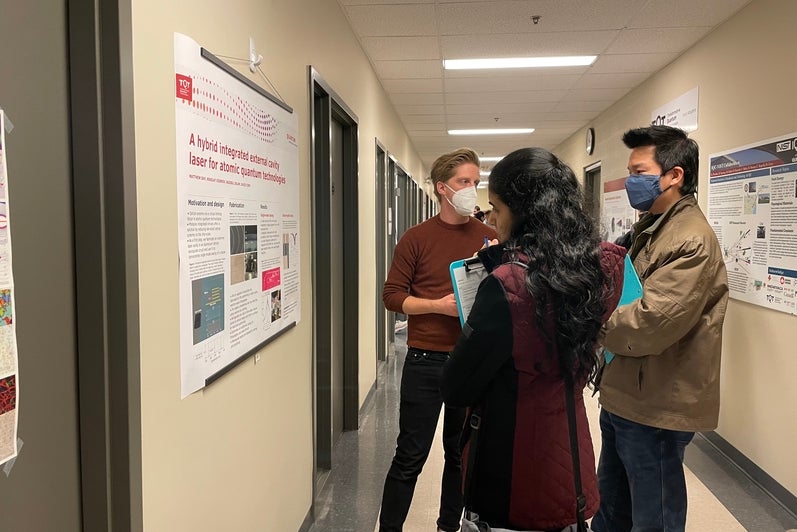 A group of people looking at scientific posters in a hallway. 
