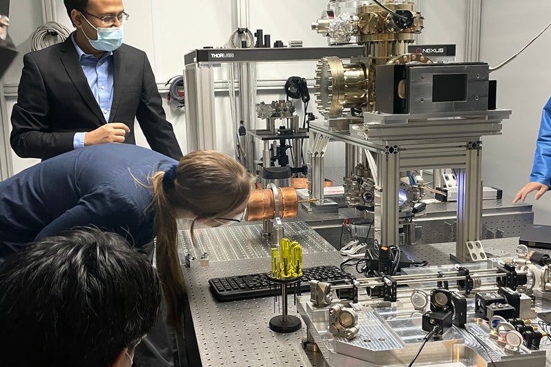 A person looking through an equipment as another stands behind them. 