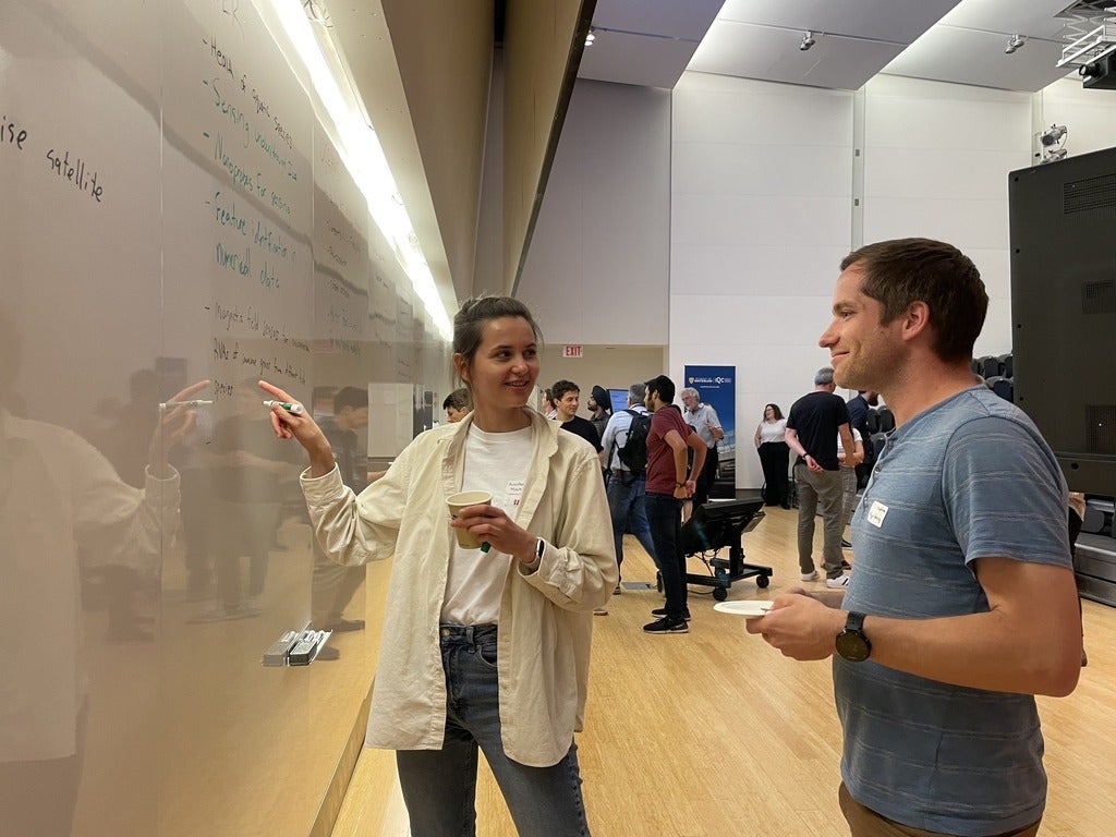 Two people discussing ideas in front of a whiteboard.