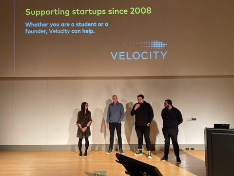 Four speakers in front of a large projector