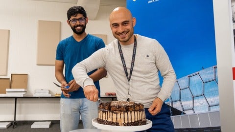 Two people cutting a chocolate cake. 