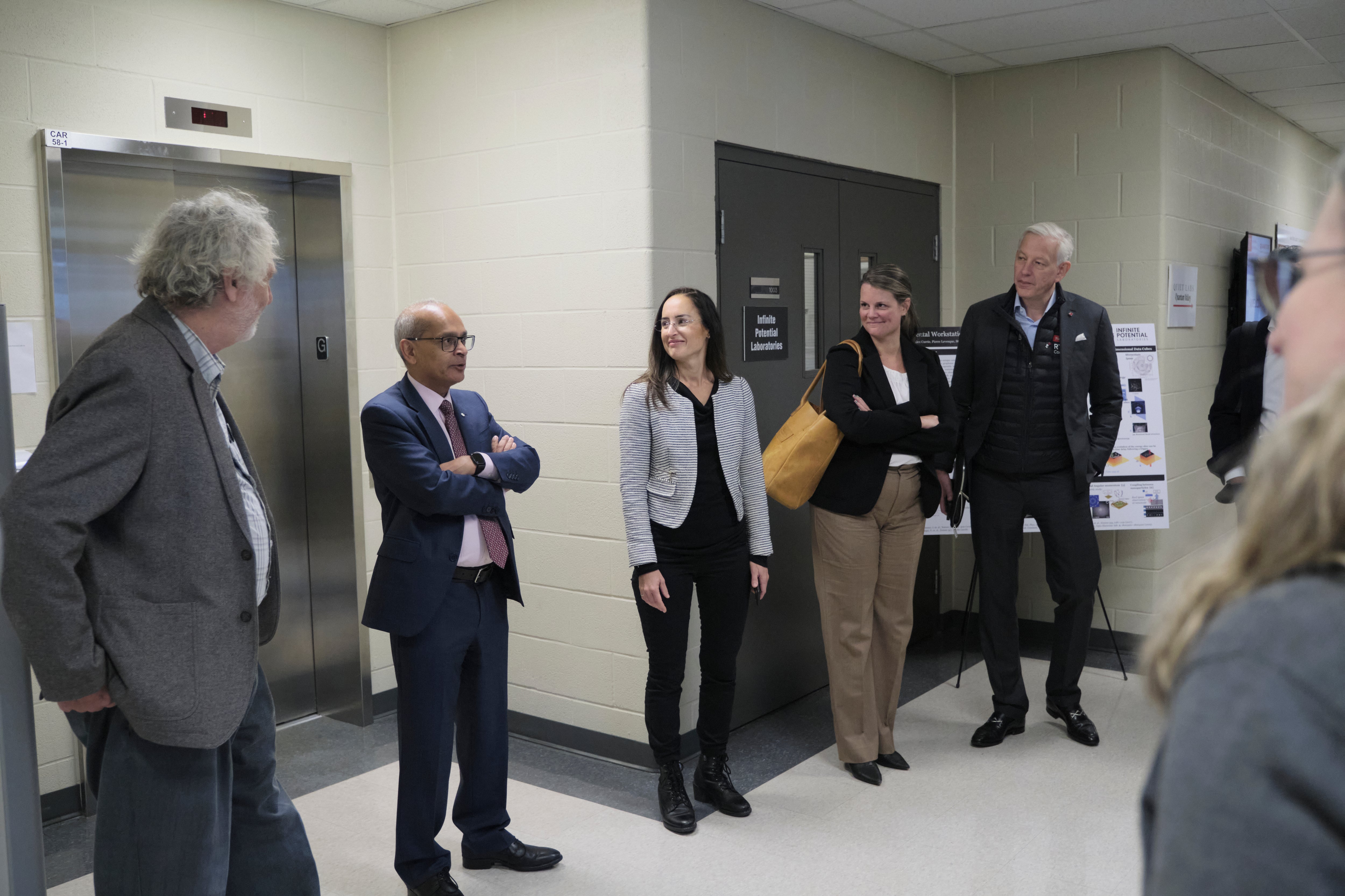 A group of people talking in front of an elevator.