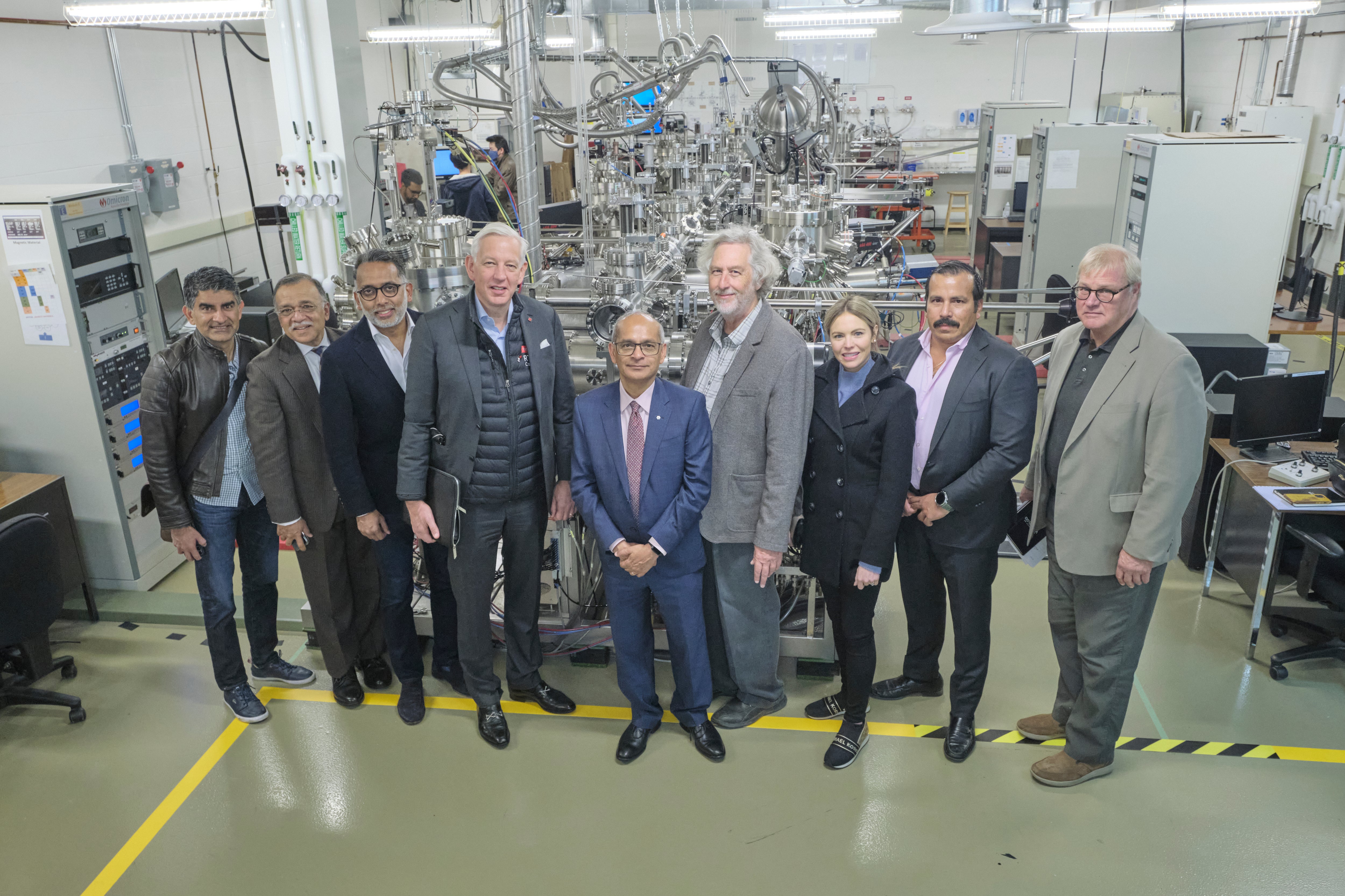 A group of people standing in front of lab equipment. 