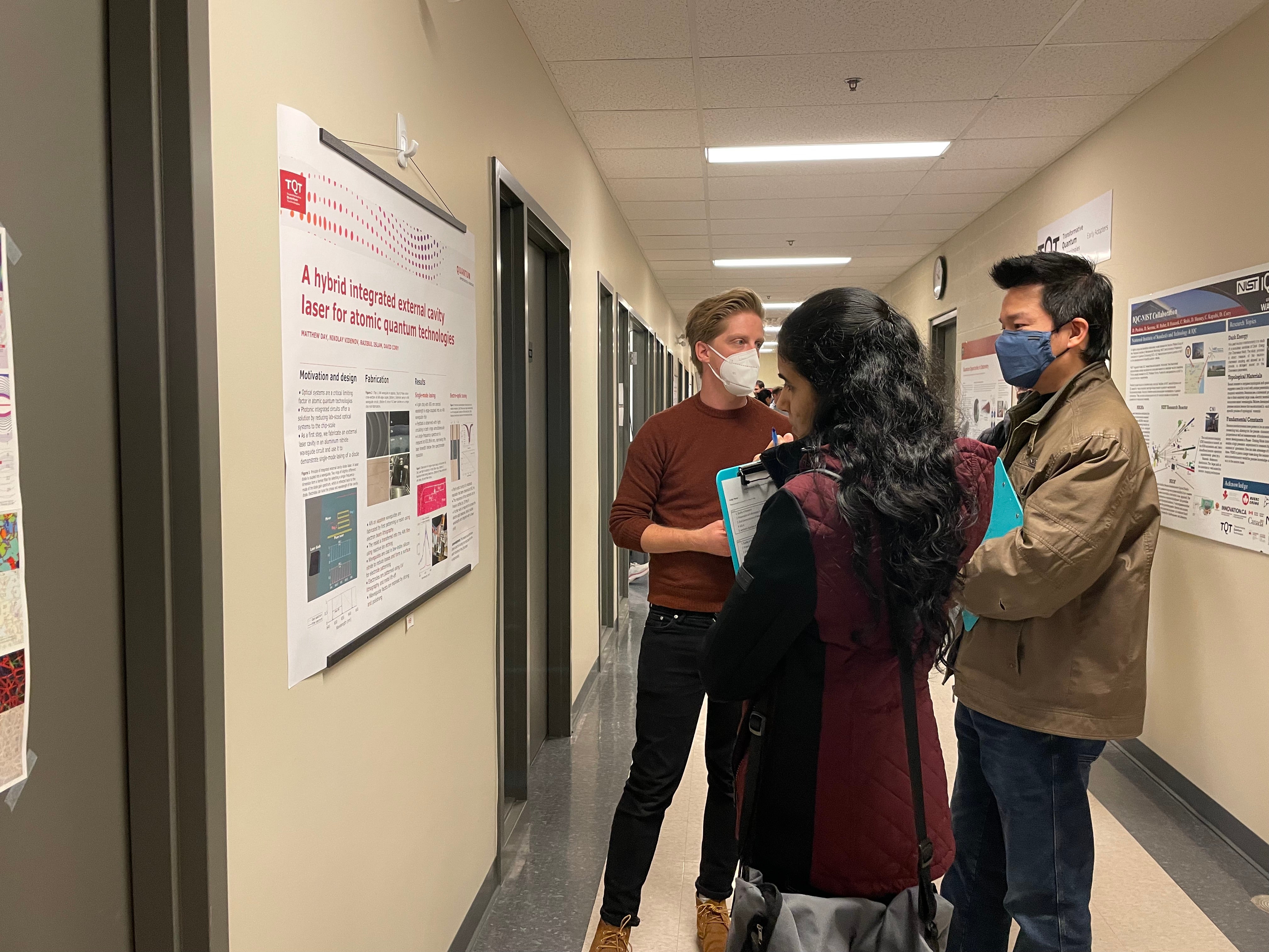 A group of people looking at scientific posters in a hallway. 