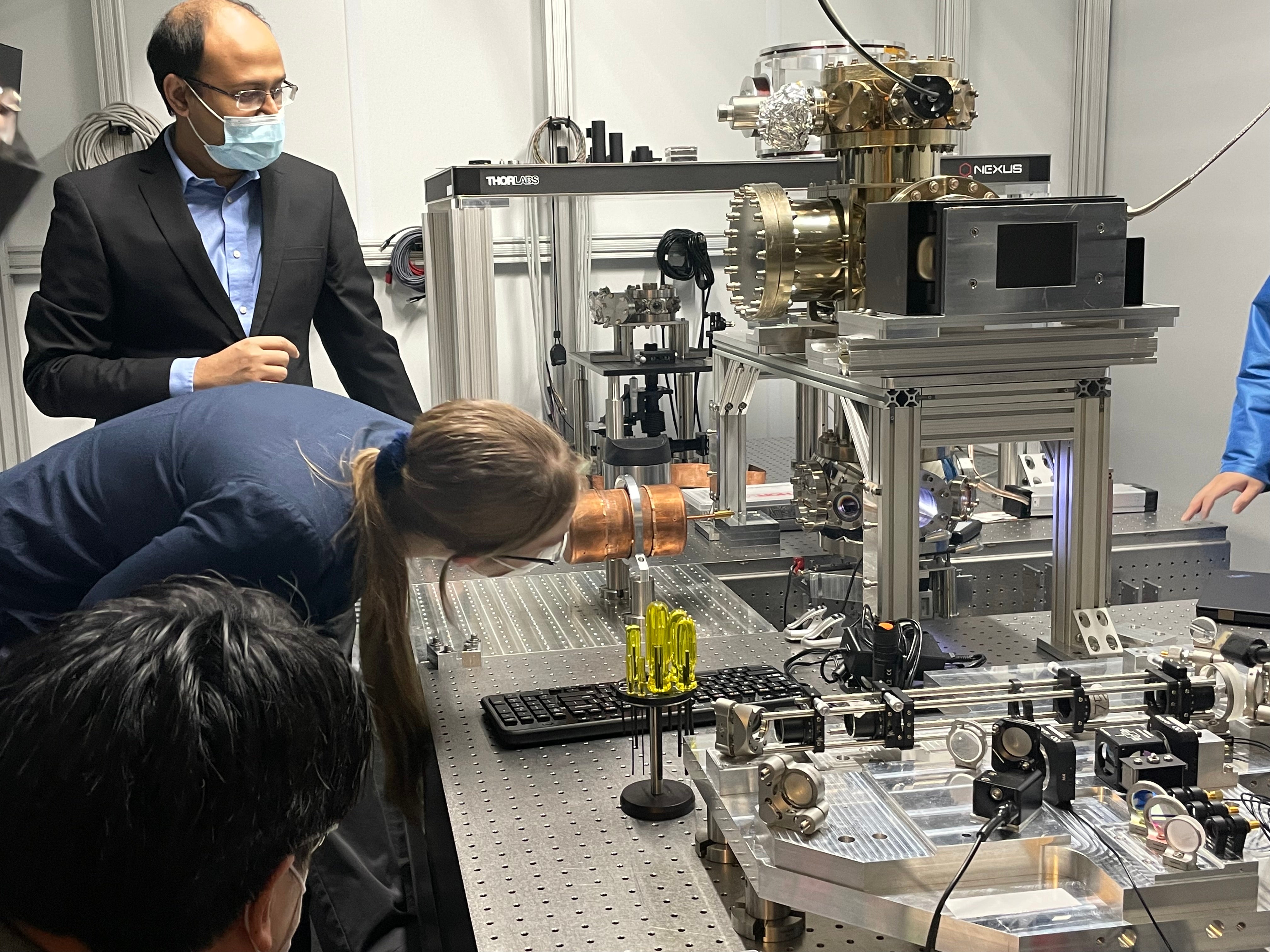 A person looking through an equipment as another stands behind them. 