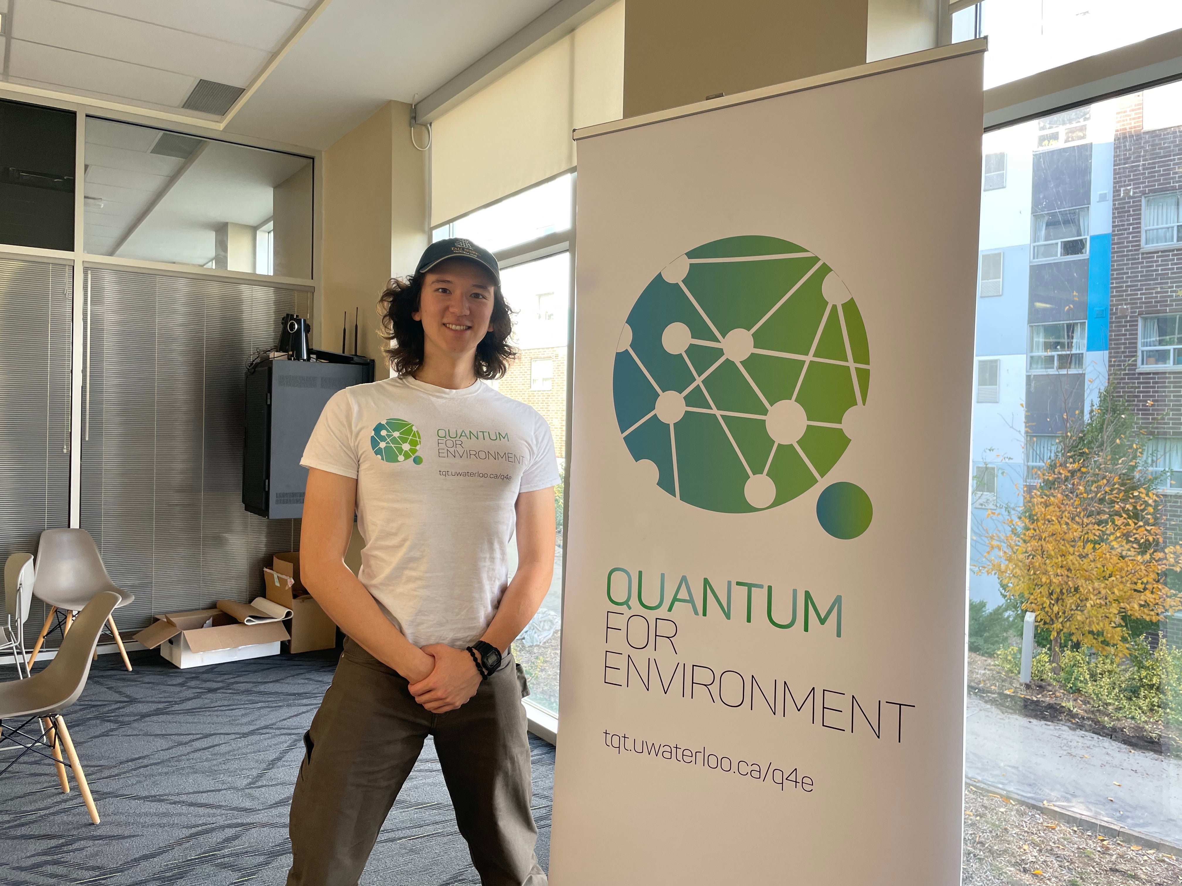 A person posing with the Quantum for Environment banner. 