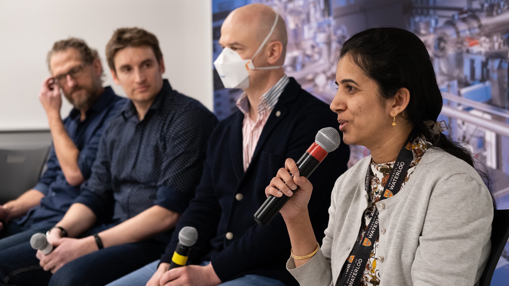 One of four panelists speaking into the microphone. 