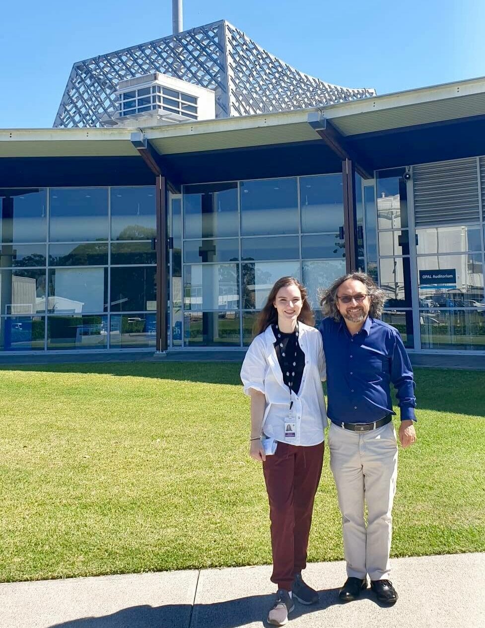 Two people standing in front of a lawn.