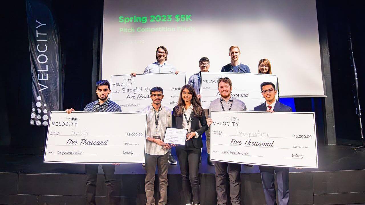 9 people standing with giant cheque awards. 