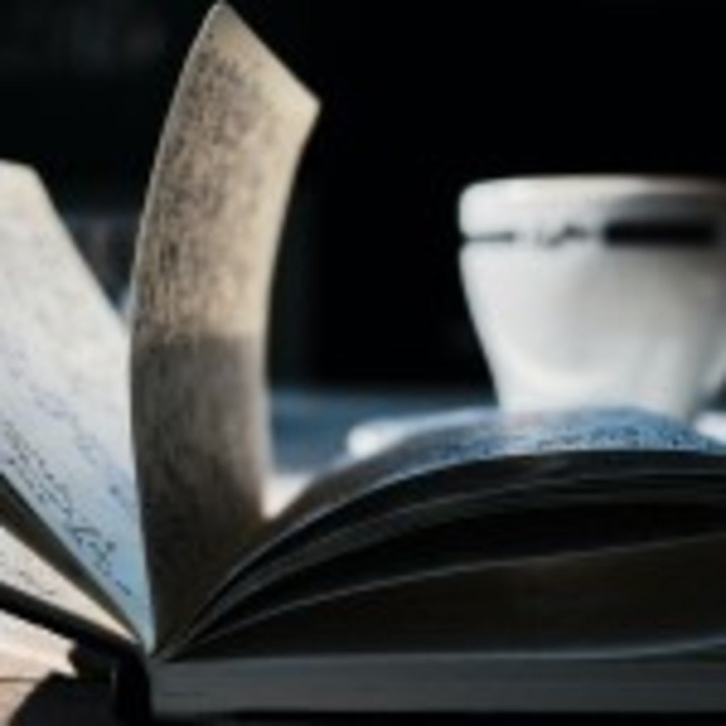 Open journal with handwriting and teacup in the background