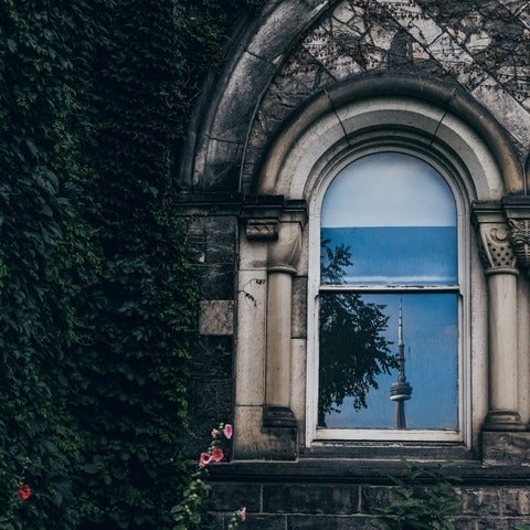 Old building with ivy and flowers around it with reflection of CN Tower in window, by Roberto Ourgant, Unsplash