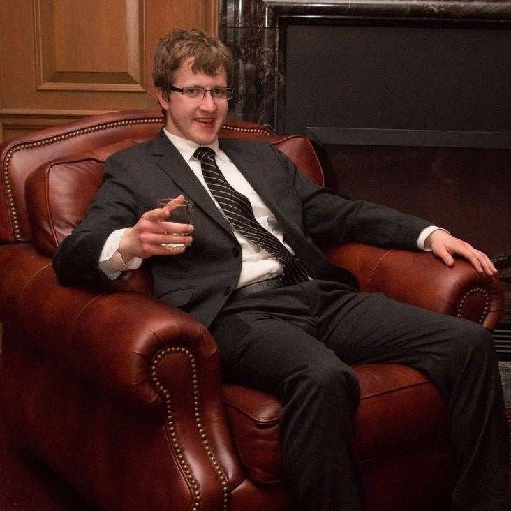 James Howey sitting with drink on leather chair