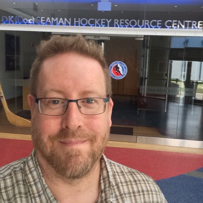 Jonathon Jackson headshot in front of hockey arena