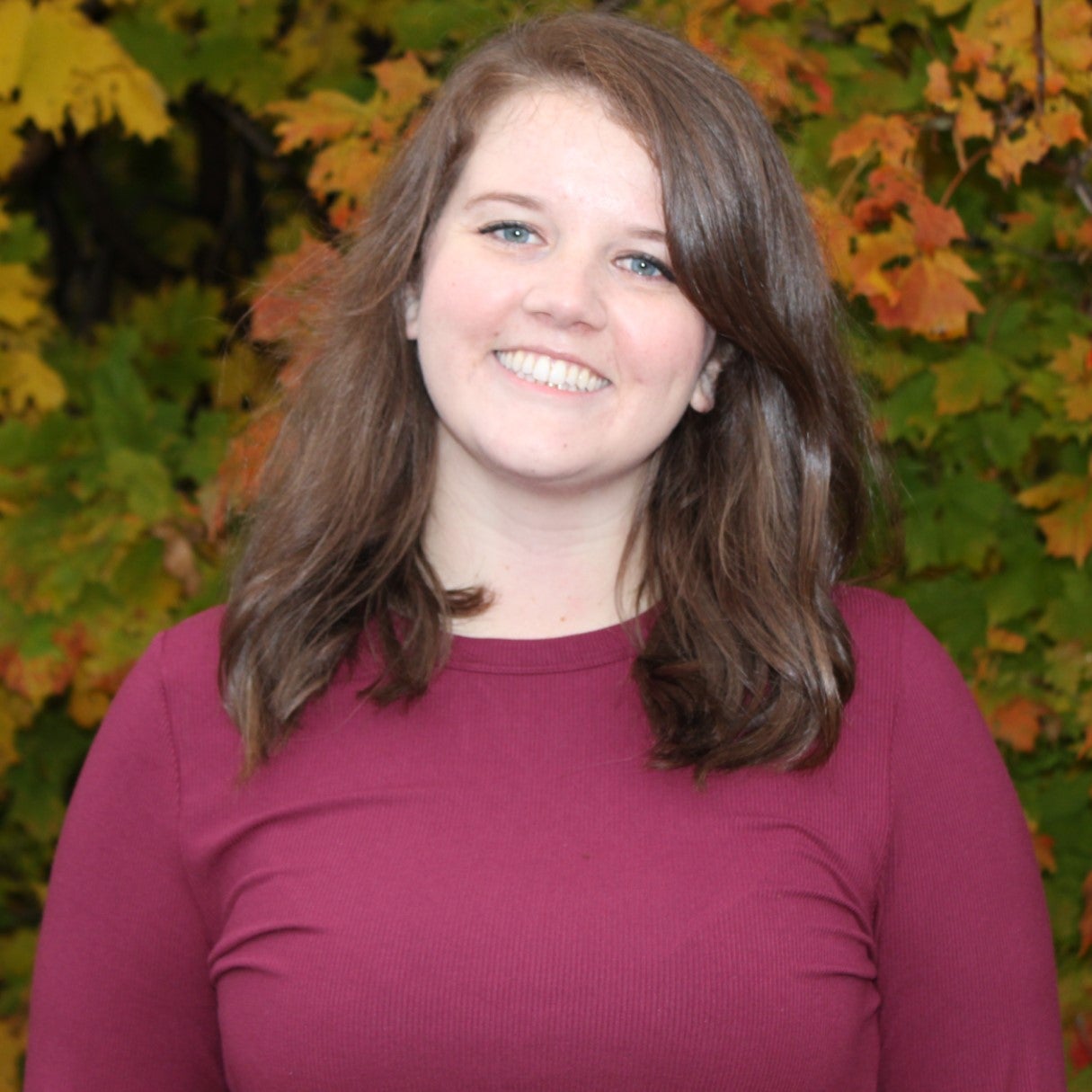 Mallory Davies head shot, autumn leaves in background