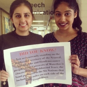 two female student hold territorial ackowledgement sign