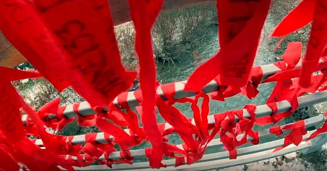 red ribbons with names tied to bridge railing
