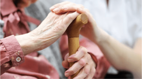 older adult holding stick and younger individual giving comfort