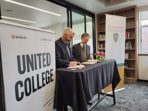 Richard Myers and Peter Meehan signing papers in the St. Jeromes Library 