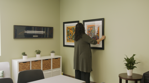 Woman putting up art print onto wall