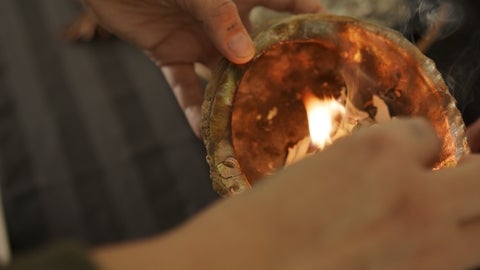 close up of hands lighting sage in a shell