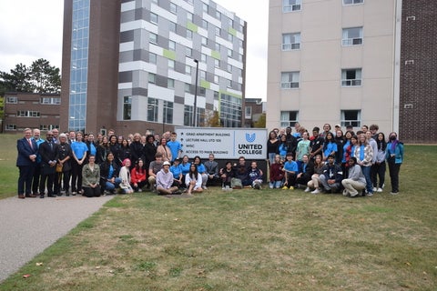 Students and staff gather around the new United College sign to celebrate the rebrand from St. Paul's to United College.