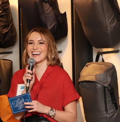 Katie speaking into a microphone and holding a thank you card 