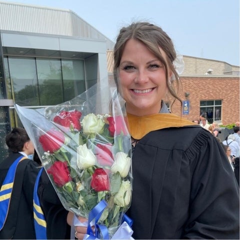 Liz holding a bouquet of flowers and smiling at the camera