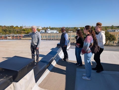 Instructor John Abraham and several students are hosted by Bruce Taylor for a guided tour of Enviro-stewards' blue roof