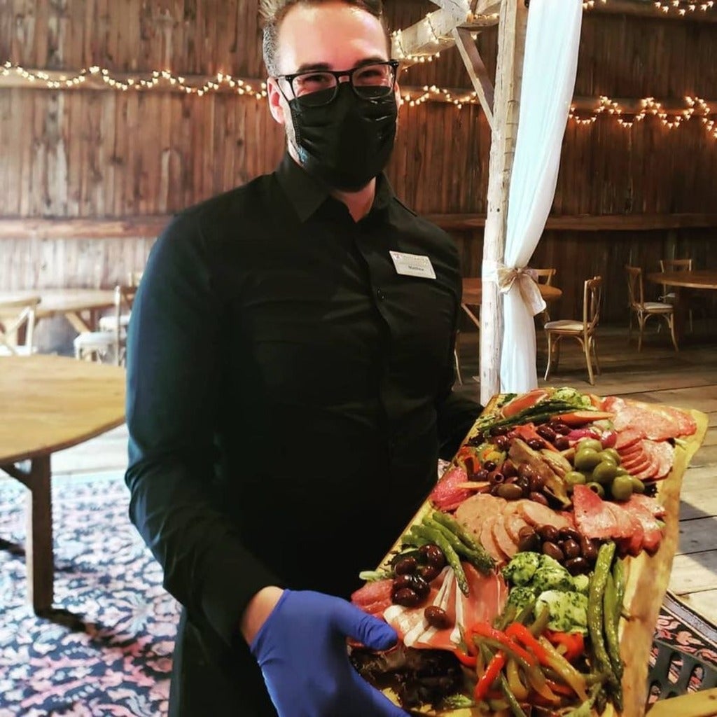 staff from brown's wearing a mask and showcasing charcuterie board