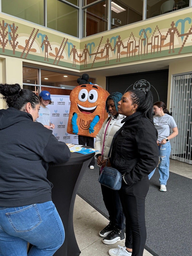 A prospective student and parent receiving information from a United College representative 