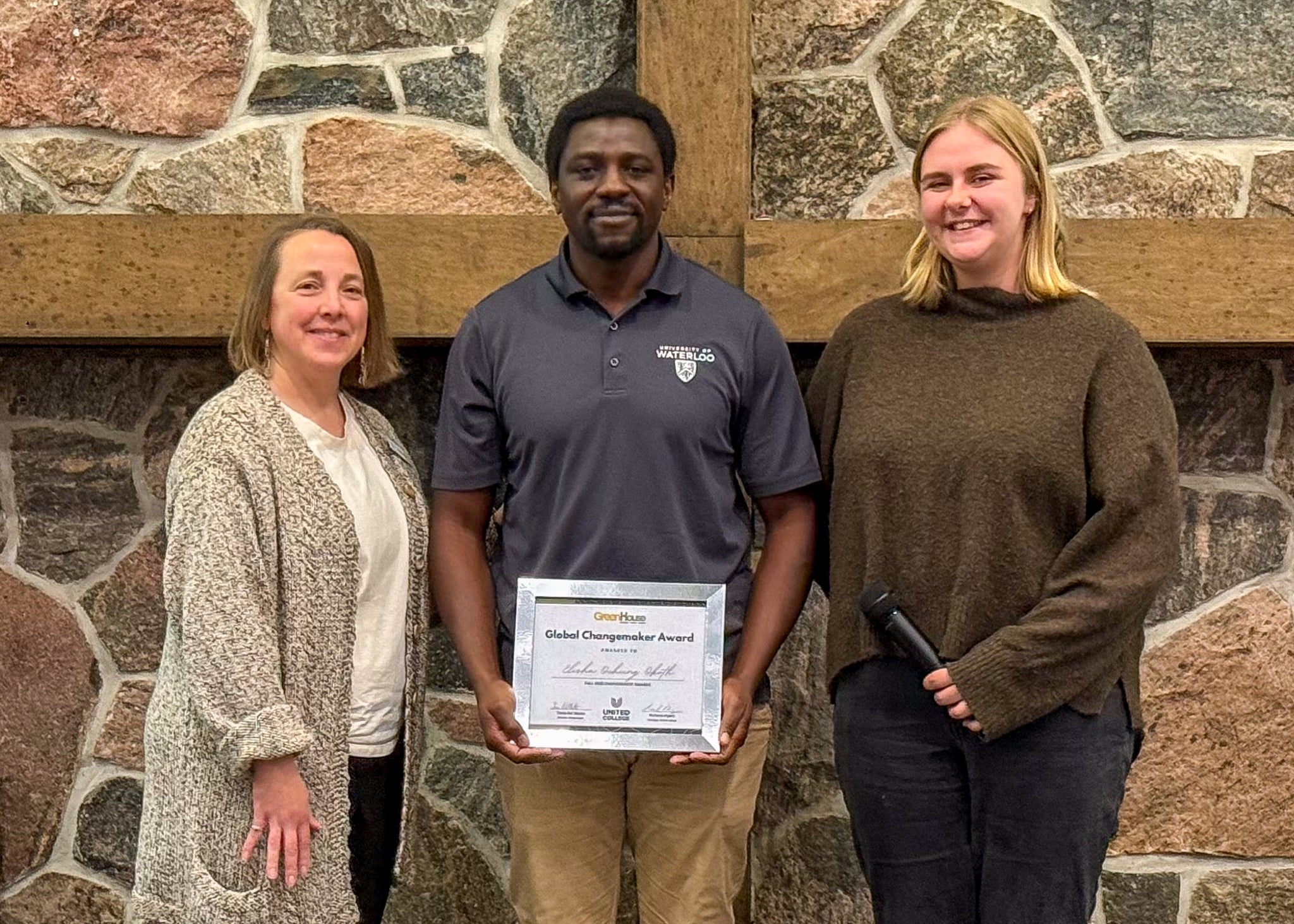 Three people stand together; the center person holds a Global Changemaker Award.