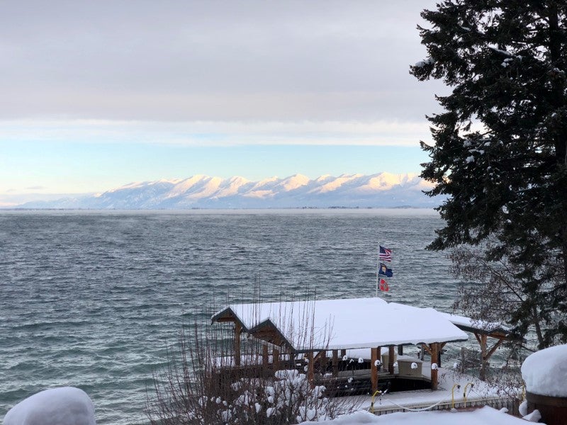 A snowy dock on Flathead Lake with snowcapped mountains in the background