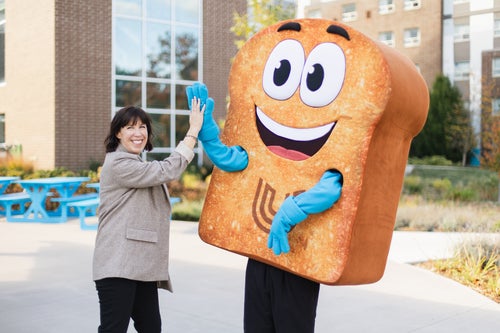 Tracy Penny Light high-fiving with Toasty the mascot. 